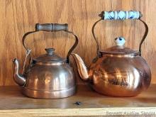 Pair of copper colored tea kettles, larger measures 9" over handle. Smaller has wooden handle and