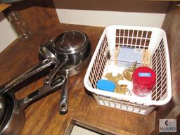 Contents of kitchen cabinet includes pots pans and cake pans