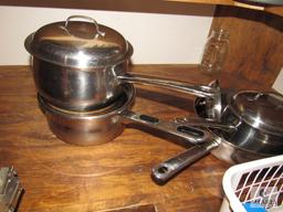 Contents of kitchen cabinet includes pots pans and cake pans