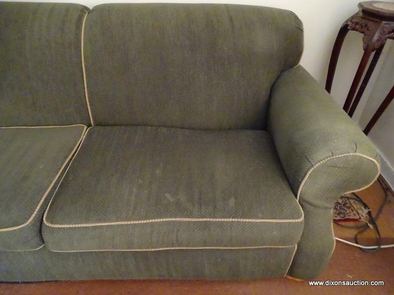 (LR) GREEN 2 CUSHION SOFA. HAS BUN FEET AND TRIMMED WITH TAN PIPING. 88"X44"X36". GOOD USED