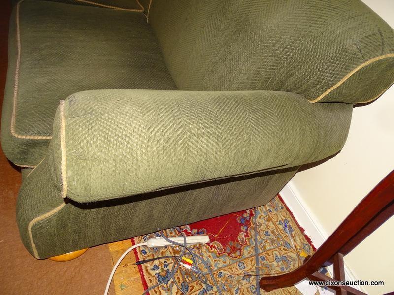 (LR) GREEN 2 CUSHION SOFA. HAS BUN FEET AND TRIMMED WITH TAN PIPING. 88"X44"X36". GOOD USED