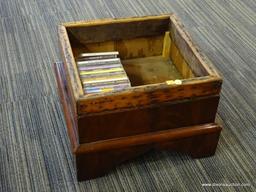 FLAME MAHOGANY FOOTSTOOL/BOX; OPEN TOP BOX HAS A SCALLOPED APRON AND A FOOTED BASE. CONTENTS