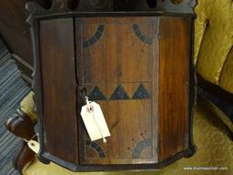 WOODEN VINTAGE HANGING CORNER CABINET; WITH KEY IN KEYHOLE ON FRONT. CARVED BACKSPLASH DESIGN FLOWS