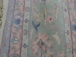 HAND KNOTTED ORIENTAL AREA RUG WITH SOME STAINING. IS IN PASTEL GREENS, YELLOWS, AND PINKS. MEASURES