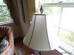 (FAM) BRASS TONE TABLE LAMP; WHITE BELL SHAPED SHADE SITTING ON A TALL CANDLESTICK STYLE BODY WITH