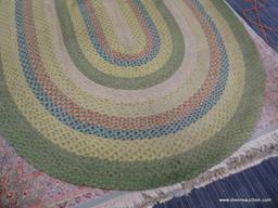 BRAIDED RUG; OVAL SHAPED BRAIDED RUG IN HUES OF GREEN, YELLOW, RED, AND BLUE. MEASURES 8 FT 7 IN X