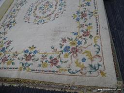 hand knotted area rug; cream colored floral rug with pink, yellow and blue flowers. has fringe