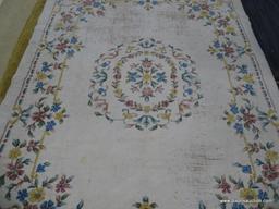 hand knotted area rug; cream colored floral rug with pink, yellow and blue flowers. has fringe