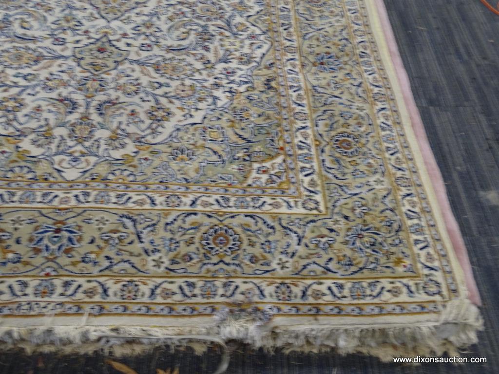 HAND KNOTTED AREA RUG; FLORAL AREA RUG IN HUES OF TAN, CREAM, BLUE, AND RED, WITH FRINGE ON BOTH