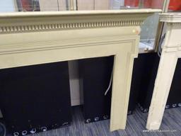 VINTAGE FIREPLACE MANTELS; CREAM/PALE YELLOW COLORED WOODEN MANTEL WITH DENTAL MOLDING AROUND THE