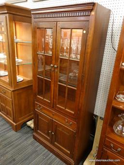 (R1) WOODEN DISPLAY CABINET; CABINET WITH DENTAL MOLDING SITTING ABOVE 2 GLASS PANELED CABINET DOORS