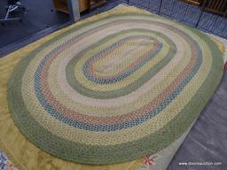 OVAL RUG; HAS A MULTI COLORED, ROPE LIKE RING DESIGN TO INCLUDE MULTIPLE TONES OF GREEN, YELLOW,