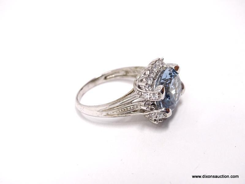 .925 STERLING SILVER RING WITH LARGE CENTER AQUAMARINE SURROUNDED BY SMALL CZ GEMSTONES. MADE BY