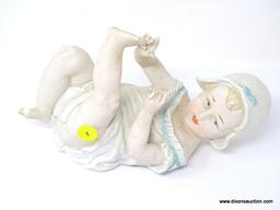 FIGURINE OF A BABY LAYING ON HER BACK PLAYING WITH HER TOES. MEASURES 9 IN X 5 IN. IS MISSING THE