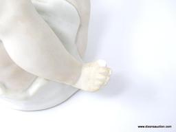 FIGURINE OF A BABY LAYING ON HER BACK PLAYING WITH HER TOES. MEASURES 9 IN X 5 IN. IS MISSING THE