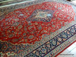 HANDMADE PERSIAN IN RED, BLUE, AND IVORY WITH LARGE CENTER MEDALLION. HAS DAMAGE. MEASURES