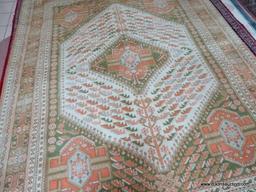 HANDMADE ORIENTAL RUG IN GREEN, ORANGE, AND IVORY. MEASURES APPROXIMATELY 8 FT 11 IN X 11 FT 9 IN.