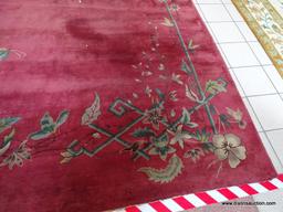 VINTAGE MACHINE MADE ORIENTAL RUG IN MAROON AND GREEN. SHOWS MOTH DAMAGE. MEASURES APPROXIMATELY 8