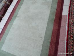 ESTATE OWNED HAND TUFTED RUG IN IVORY, GREEN, AND MAROON. MEASURES APPROXIMATELY 5 FT 1 IN X 7 FT 9