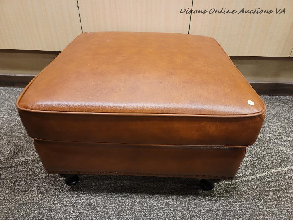 (R1) MODERN LEATHER UPHOLSTERED OTTOMAN IN BROWN WITH ESPRESSO FINISH LEGS. MEASURES 29 IN X 29 IN X