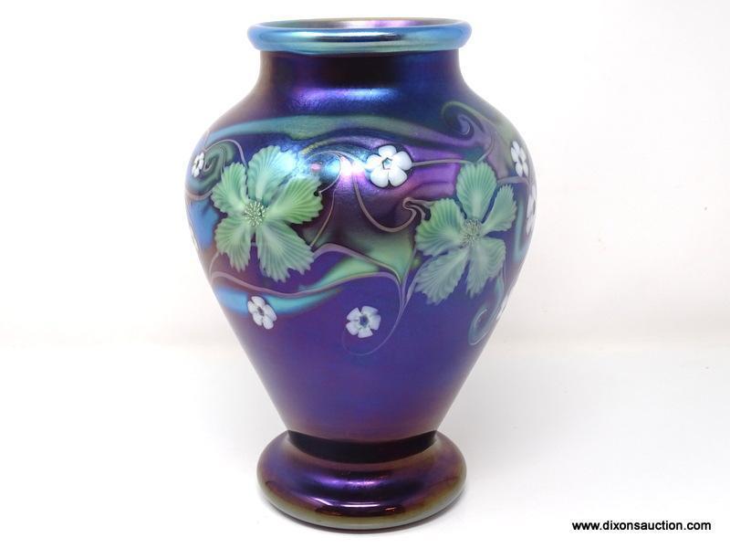 Purplish brown iridized glass with surface decoration of green and white floral motif having