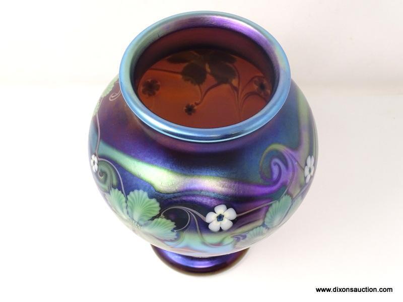 Purplish brown iridized glass with surface decoration of green and white floral motif having