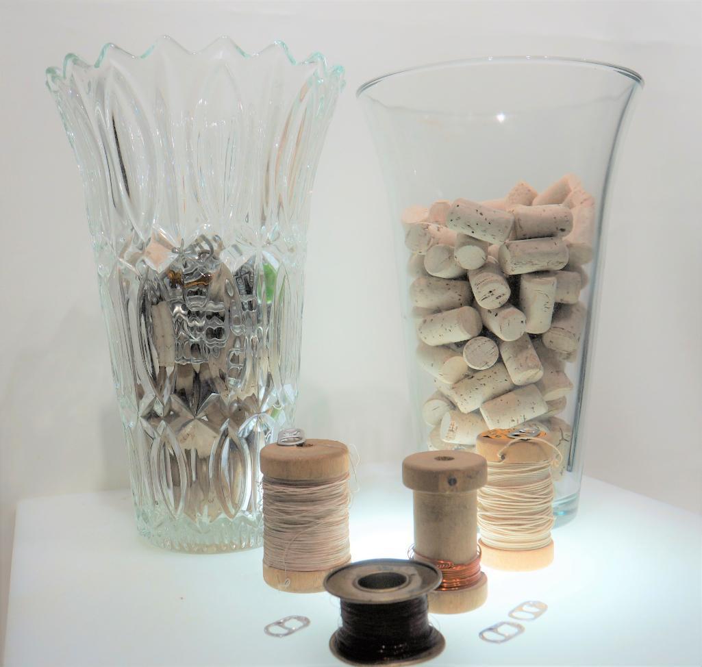 (12L) TWO TALL TAPERED GLASS VASES FILLED WITH CRAFTS SUPPLY ITEMS: CORKS, PULL TABS, WOODEN SPOOLS,