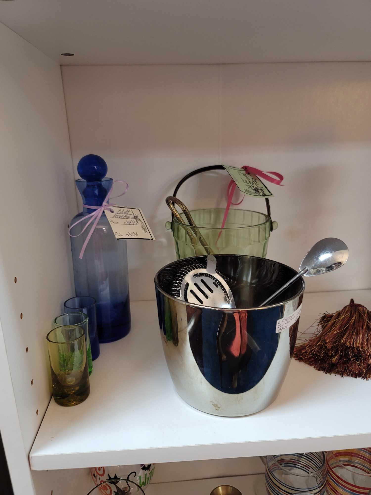 (RM1) LOWER 3 SHELVES OF BOOKCASE. INCLUDES: 3 GLASS DECANTERS, METAL ICE BUCKET AND ACCESSORIES, A