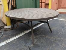 Oval shaped slatted brown metal outdoor patio table with center umbrella hole. Does show signs of