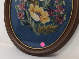 (FOYER) VINTAGE HAND STITCHED NEEDLEPOINT ART DEPICTING A FLORAL SCENE. DISPLAYED IN AN OVAL BROWN