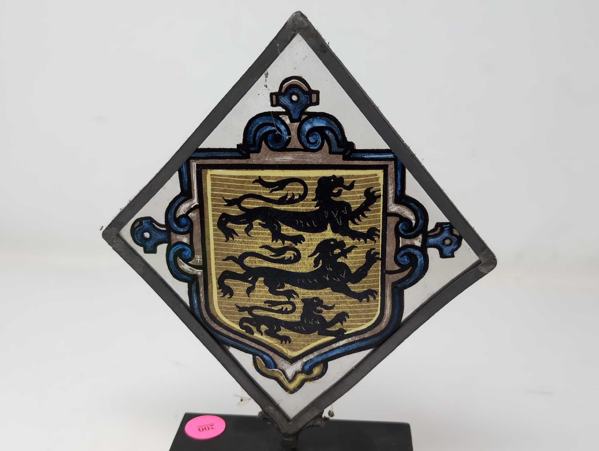(LR) VINTAGE TRIANGULAR PAINTING ON GLASS DEPICTING A THREE LION CREST. THE GLASS IS FRAMED IN A