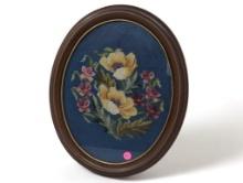 (FOYER) VINTAGE HAND STITCHED NEEDLEPOINT ART DEPICTING A FLORAL SCENE. DISPLAYED IN AN OVAL BROWN