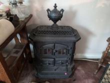 (LR) ANTIQUE URI CAST IRON VICTORIAN PARLOR WOOD STOVE WITH ELECTRIC LOGS INSIDE. MEASURES 20-1/2"W