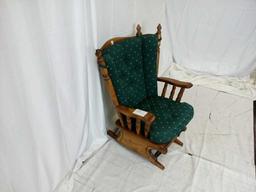 Dark oak glider rocker with green seat and back.