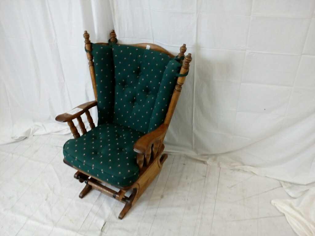 Dark oak glider rocker with green seat and back.