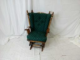 Dark oak glider rocker with green seat and back.