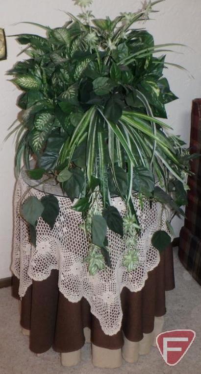 Round wood table with glass top, table coverings and artificial greenery.