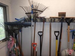 Lawn and garden tools, shovels, rakes, brooms, and decorative flags. All tools and flags on wall.