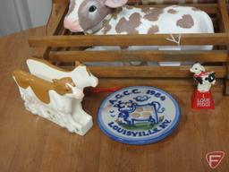 Cow items, print, napkin holder, ceramic figurines, cow bell, and wall decoration. All cow items on