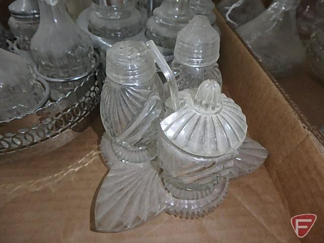 Clear glass condiment sets in metal holders and on glass trays, measuring cup, refrigerator dishes.