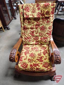 Vintage upholstered reclining chair with carved face arms