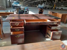 Wood desk with glass top and three drawers on the left, three drawers on the right, and a pencil