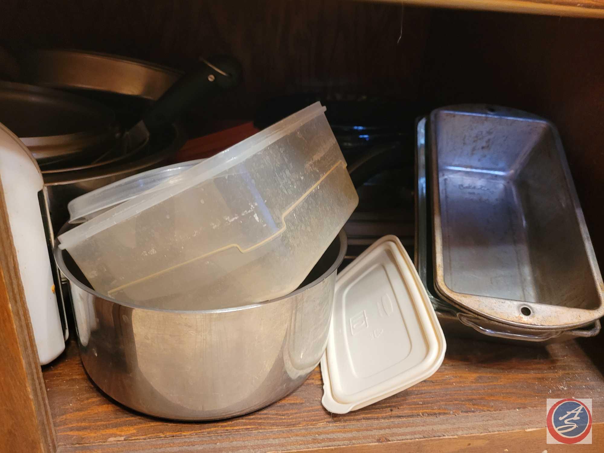 Assortment of bread pans, pots, pans, storage dishes, colander, what appears to be Tupperware, and