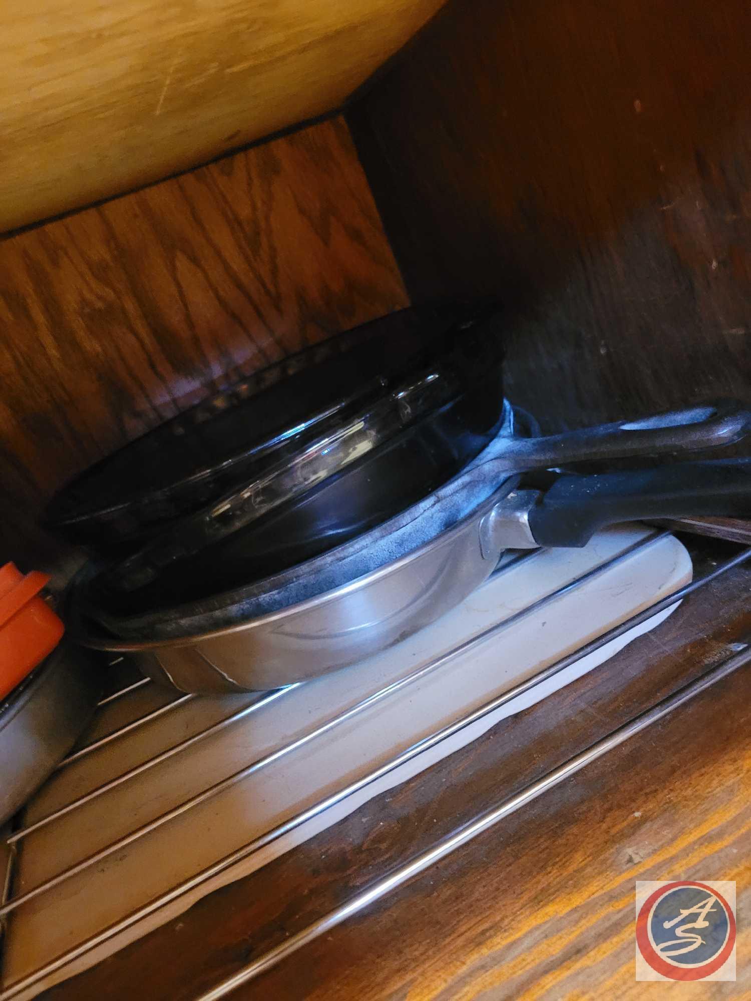 Assortment of bread pans, pots, pans, storage dishes, colander, what appears to be Tupperware, and