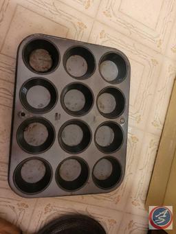 Assortment of baking pans including muffin tin, three wooden rolling pins, and a stovetop splatter