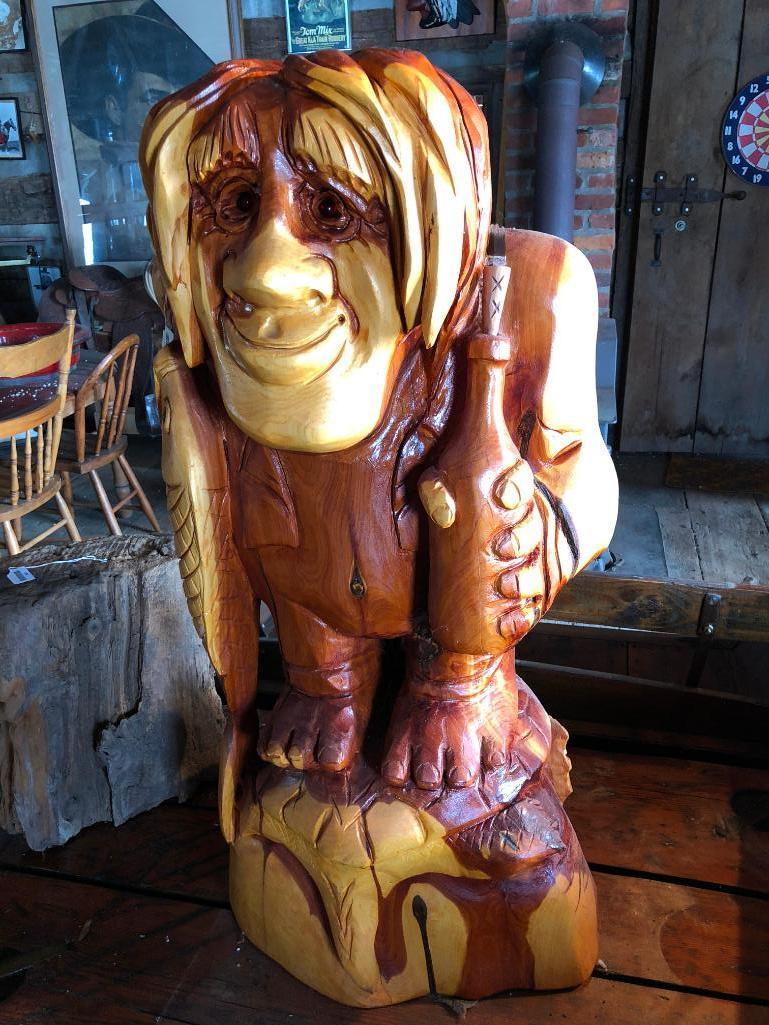 Large, wood carved figure of man with bottle and fish.