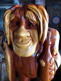 Large, wood carved figure of man with bottle and fish.