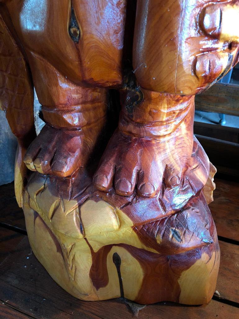 Large, wood carved figure of man with bottle and fish.