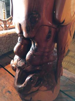 Large, wood carved figure of man with bottle and fish.