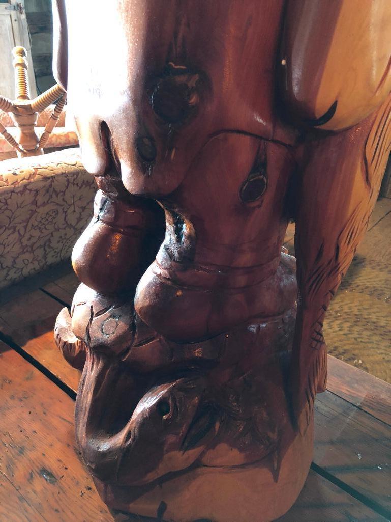 Large, wood carved figure of man with bottle and fish.